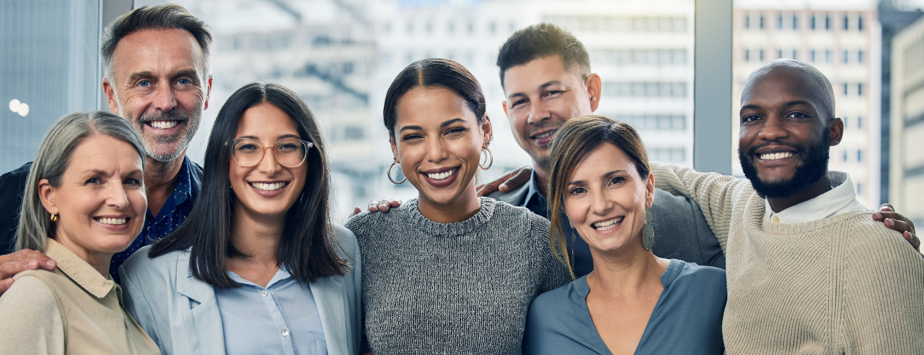 Eine diverse Menschengruppe verschiedenen Alters, Geschlechts und verschiedener Hautfarbe umarmt sich und lacht in die Kamera. - Quelle: BAB/iStock