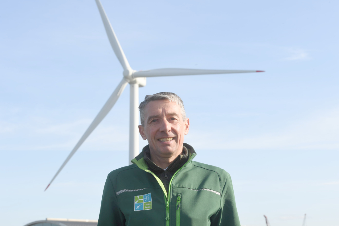 Das Bild zeigt den Geschäftsführer Andreas Wellbrock vor einem Windrad