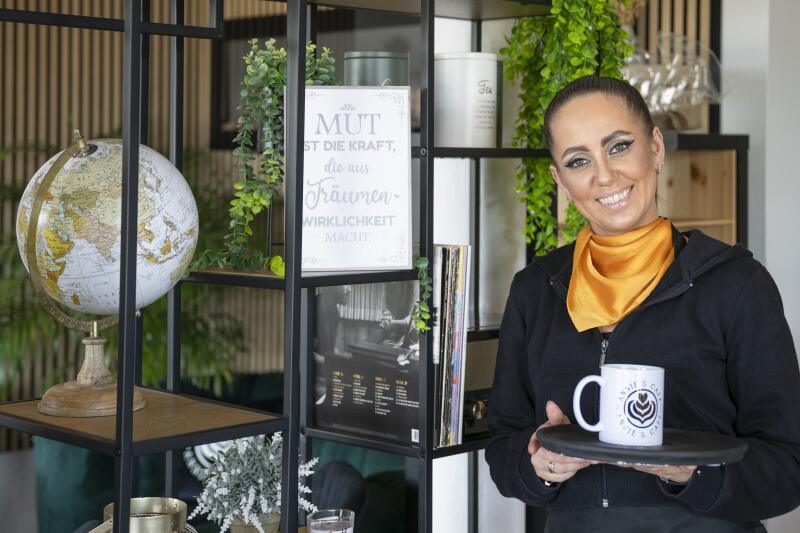 Anja Brantzen trägt ein Tablett mit einer Tasse in ihrem Café