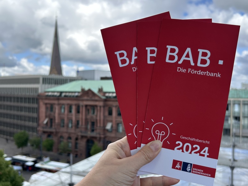 Der Flyer des Geschäftsbericht wird vor dem Bremer Marktplatz gezeigt