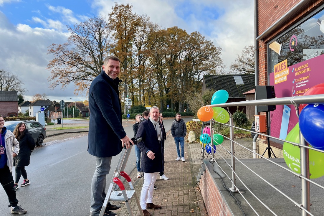Norbert Hegmann steht auf einer Leiter bei der Filialeröffnung in Axstedt. Rechts erkennt man die Tante-Enso-Schilder der Filiale.