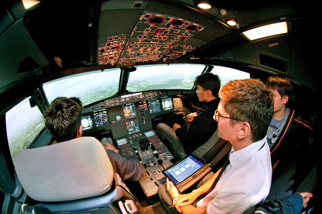 Ein Mann und drei Kinder sitzen in einem Cockpit