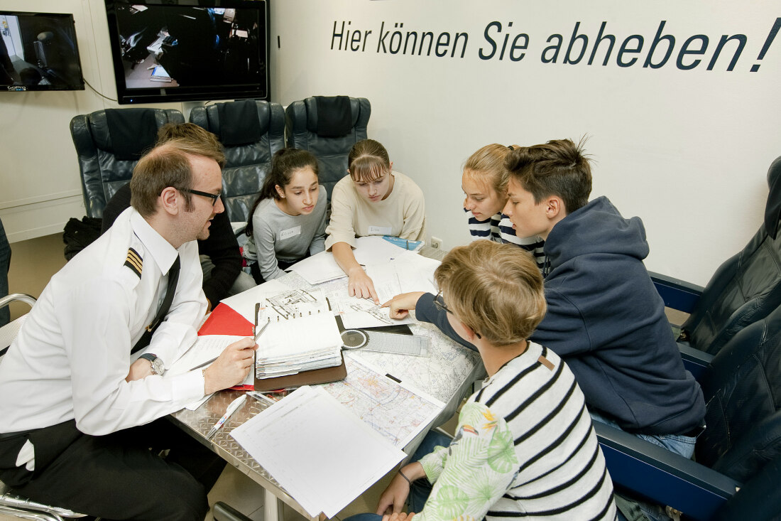 Ein Mann und einige Jugendliche sitzen um einen Tisch und lernen