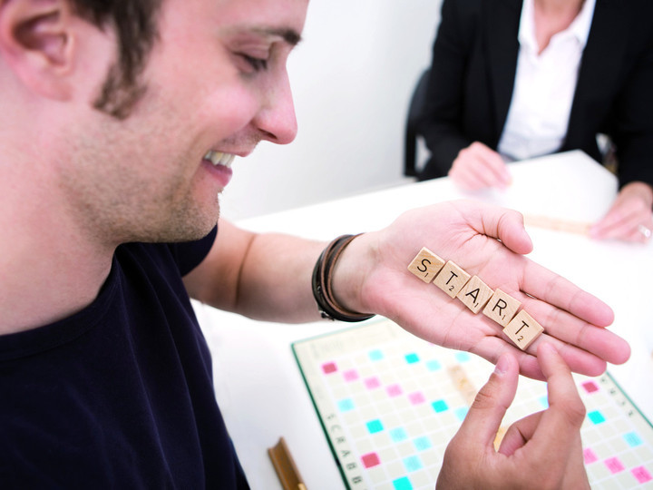 Ein Mann hält Start als Scrabble Buchstaben in der Hand 