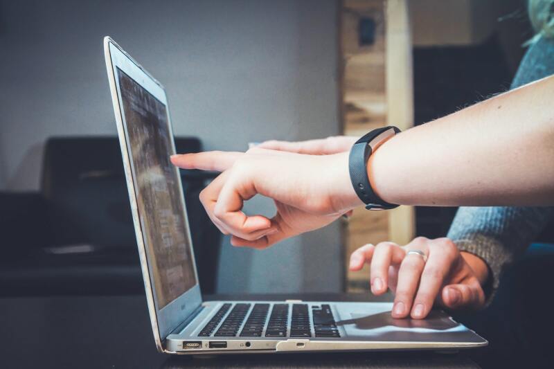 Zwei Menschen zeigen auf einen Laptop-Bildschirm